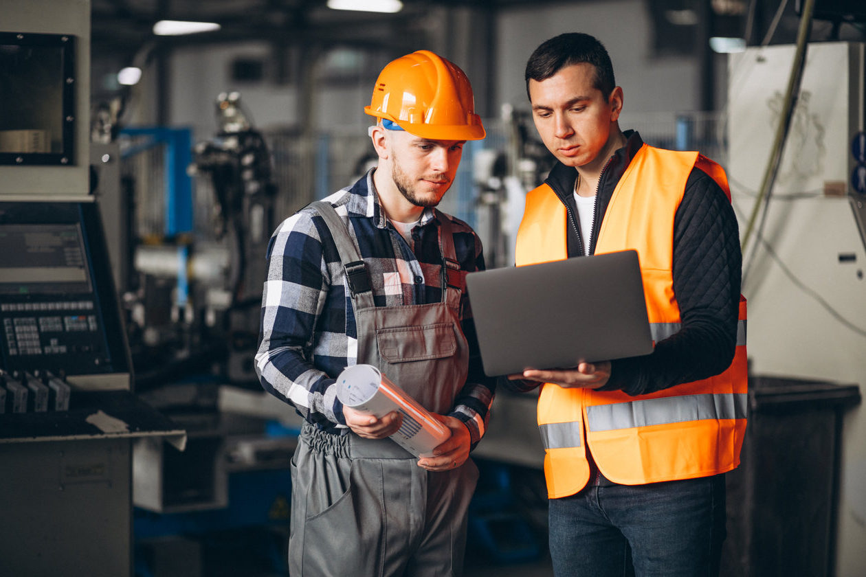 Dos trabajadores que examinan la calidad del portátil en la fábrica.