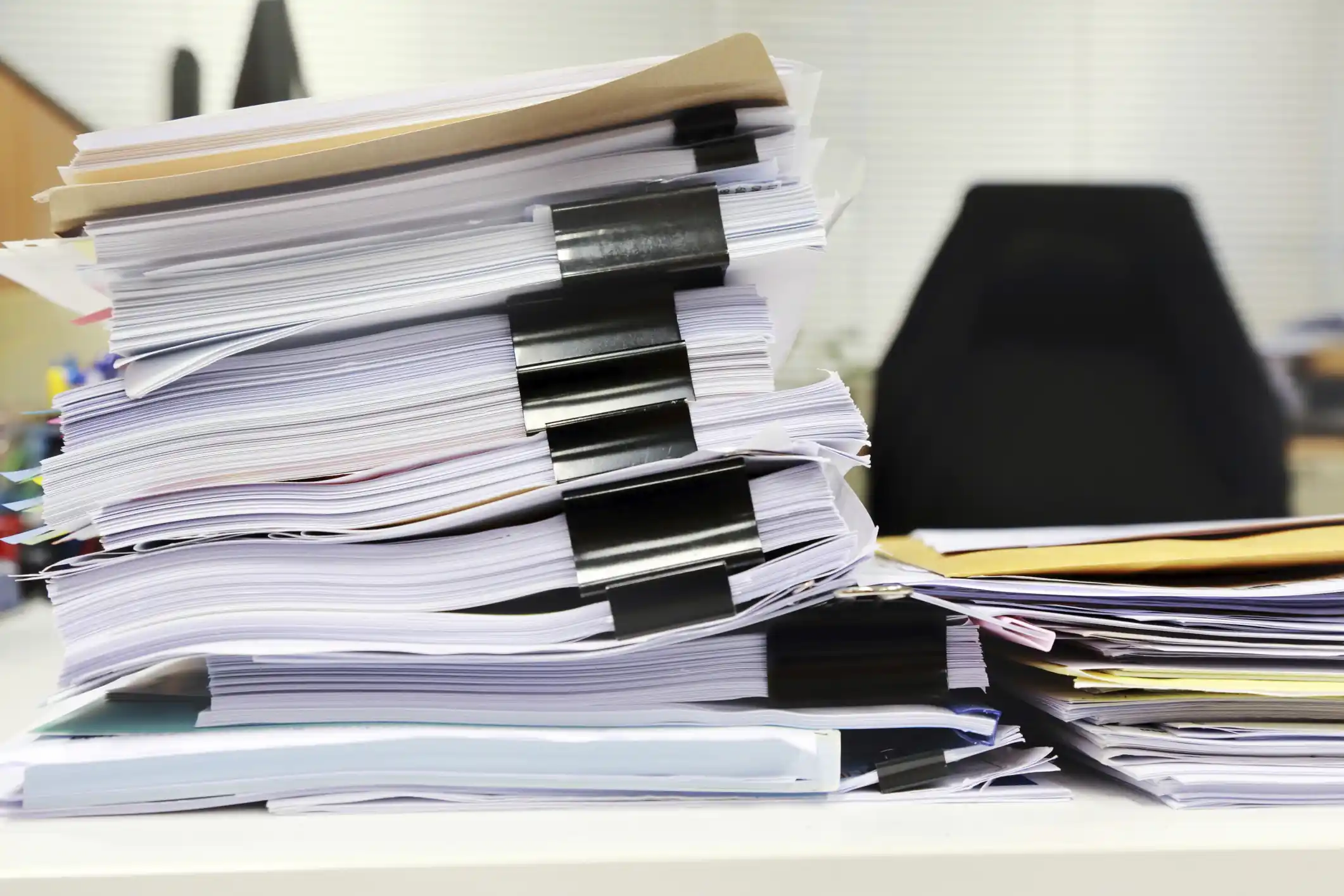 Un montón de documentos en un escritorio de oficina relacionados con la gestión de documentos.