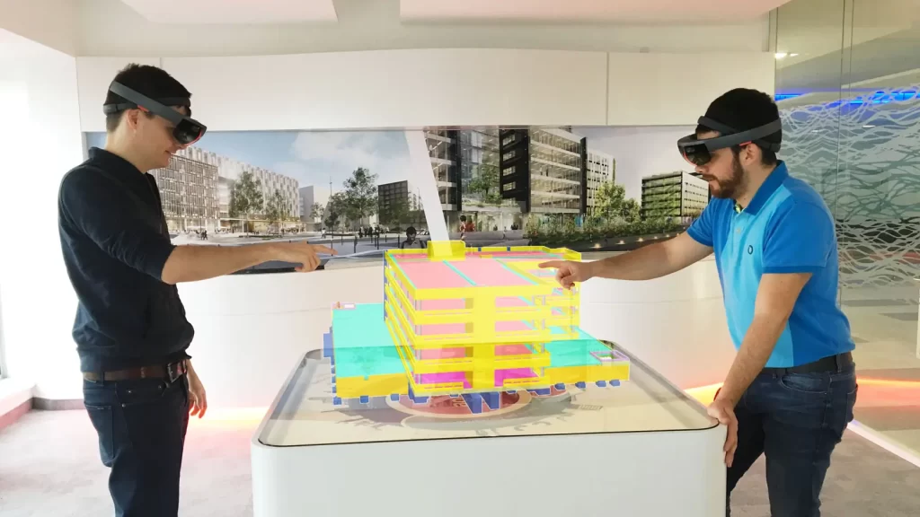 Los gemelos digitales que utilizan tecnología 3D en tiempo real visualizan a dos hombres frente a un modelo de construcción.