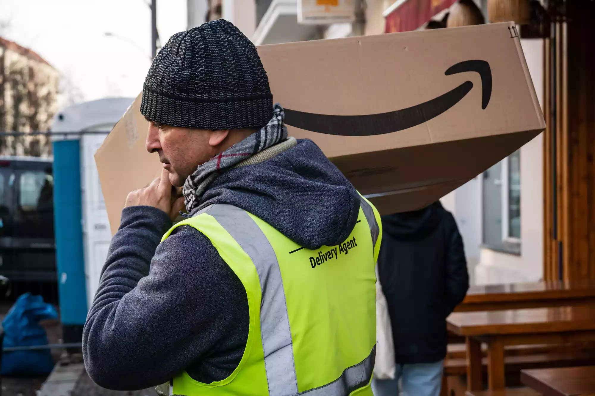 Un hombre lleva una caja con el logo de Amazon para la operación logística.